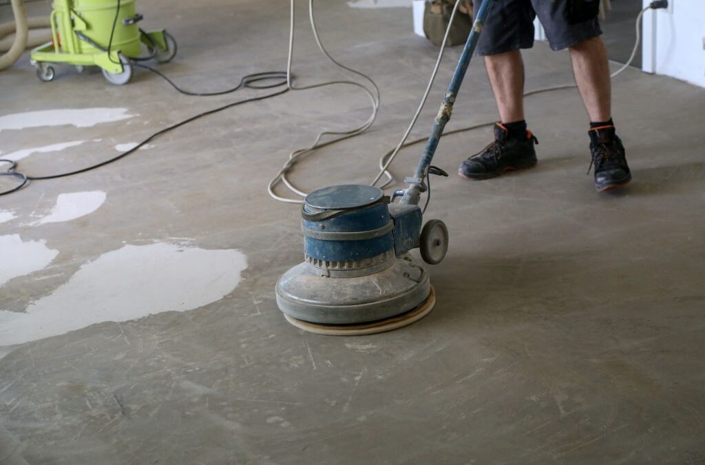 cement and concrete contractor grinding the floor using a single disc machine.